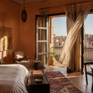 Sunlit Moroccan bedroom with sheer curtains framing morning light