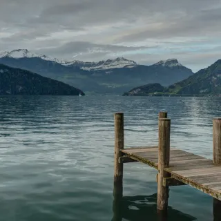 Wooden jetty leading into a still lake at dawn