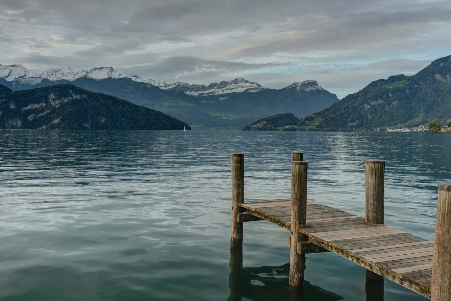 Wooden jetty leading into a still lake at dawn