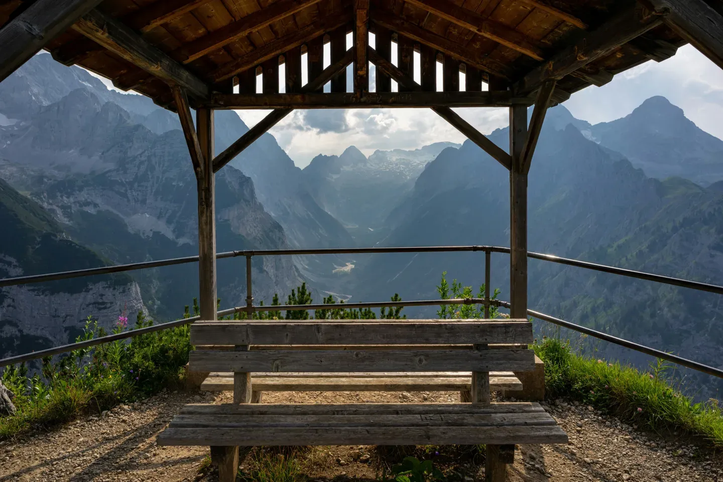 Empty bench under a wooden shelter framing a valley