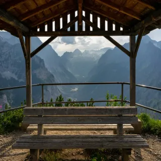Empty bench under a wooden shelter framing a valley