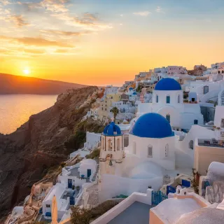 Santorini blue-domed church above the caldera at sunset