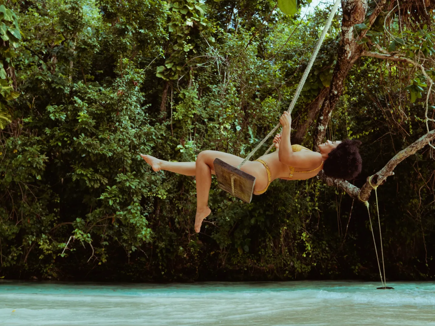 Woman on a rope swing over the river at Frenchman's Cove, Port Antonio, Jamaica