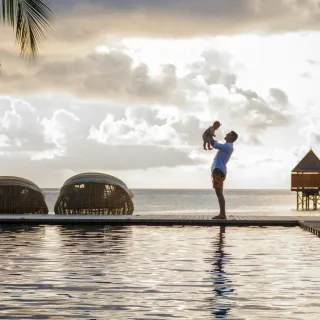 Sunset infinity pool with a parent and child