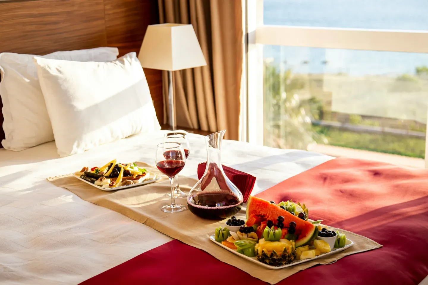 Styled bed with food, glassware and a sea view