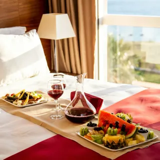 Styled bed with food, glassware and a sea view
