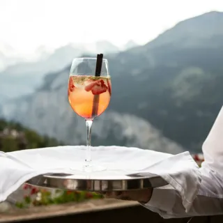 Waiter presenting a styled cocktail with a mountain backdrop