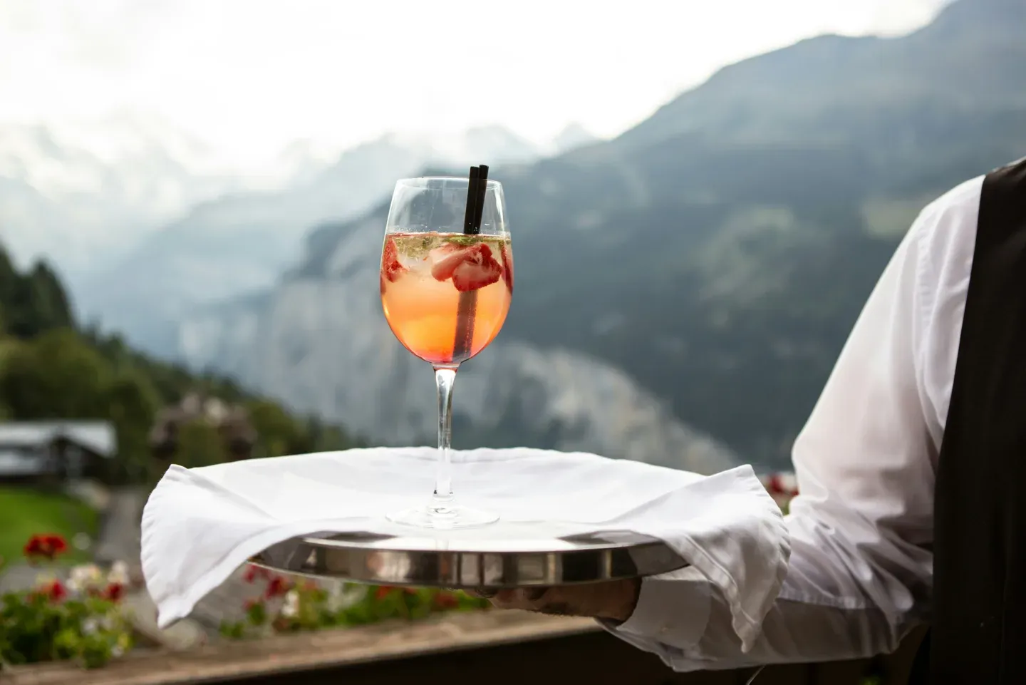 Waiter presenting a styled cocktail with a mountain backdrop
